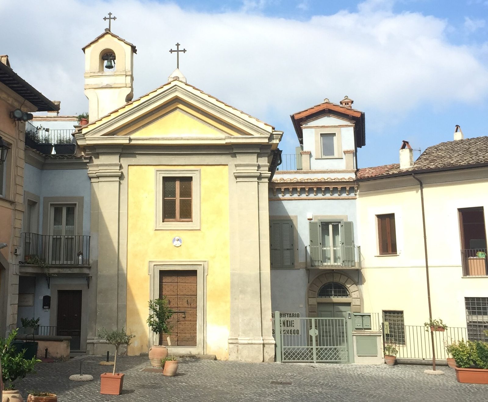 Facciata gialla dell'Oratorio della Natività a Formello, con campaniletto a vela e cortile